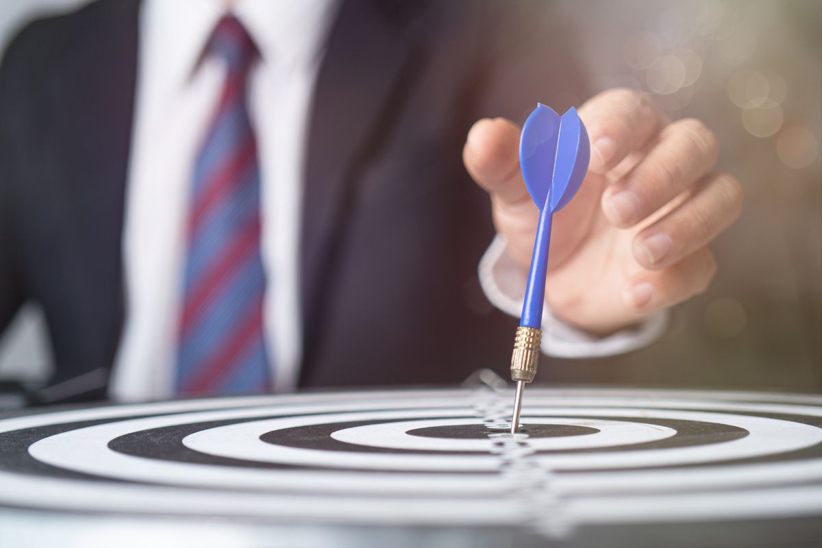 A man in a suit sticking a dart on a target to illustrate why goal setting is important to inbound marketing.