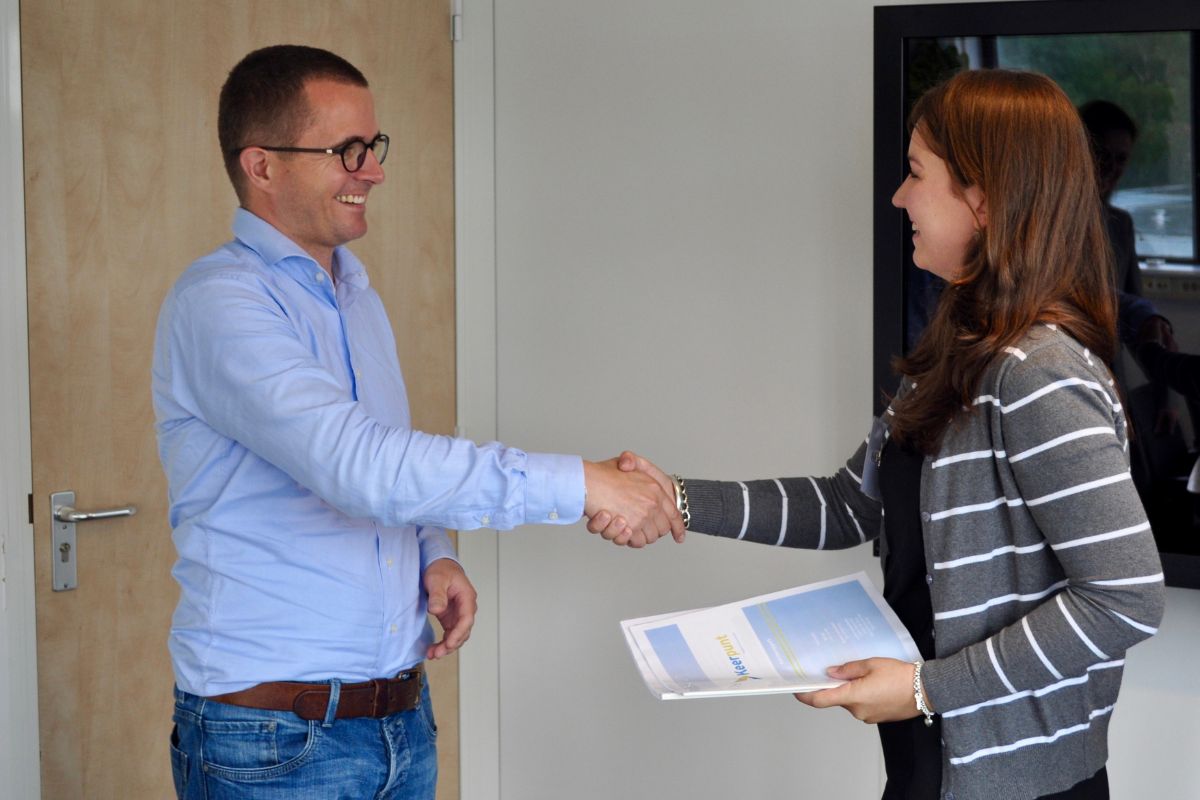 A woman with a product catalogue greeting a lead interested in making a purchase.